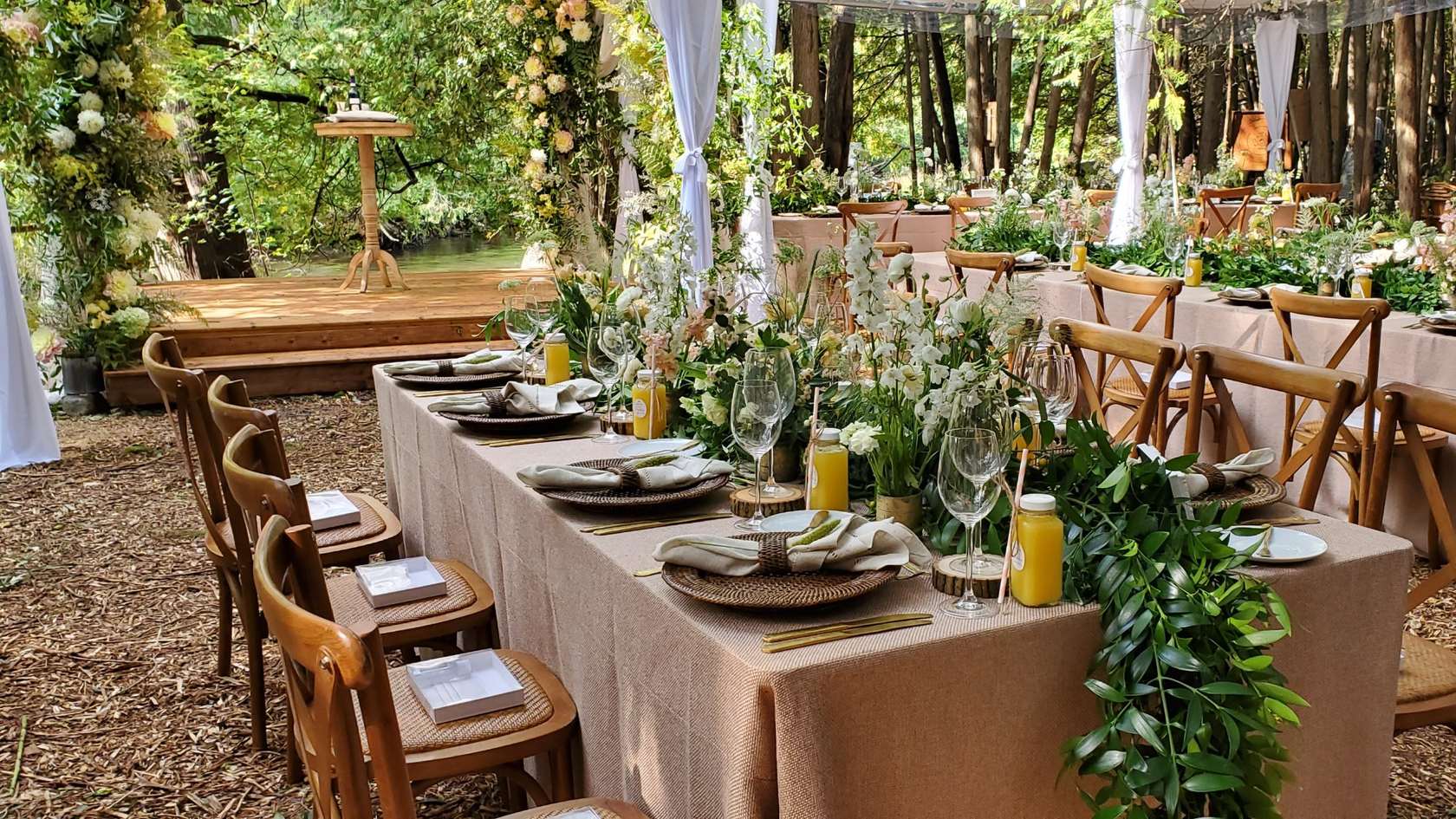 A long dinner table set among the trees for an outdoor kosher catered meal