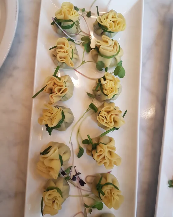 Crêpe purses tied with chives on a white platter